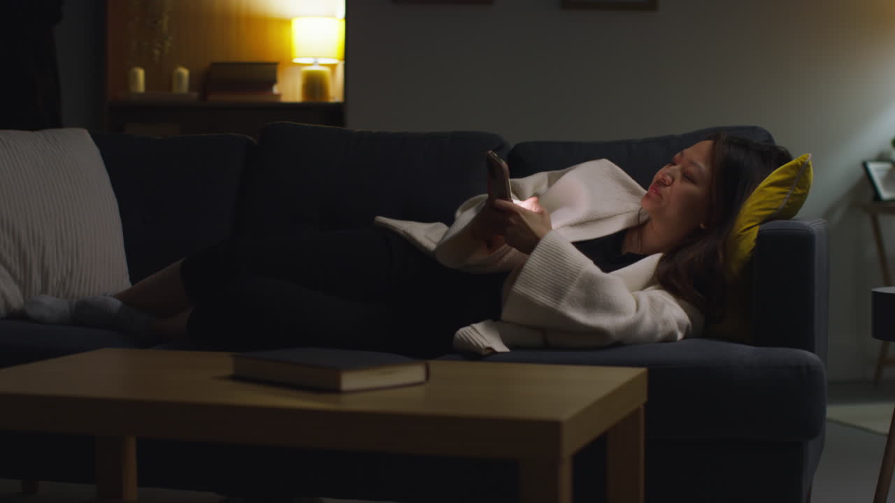 mujer que pasa la noche en casa acostada en el sofá con el teléfono móvil navegando por internet o las redes sociales 16
