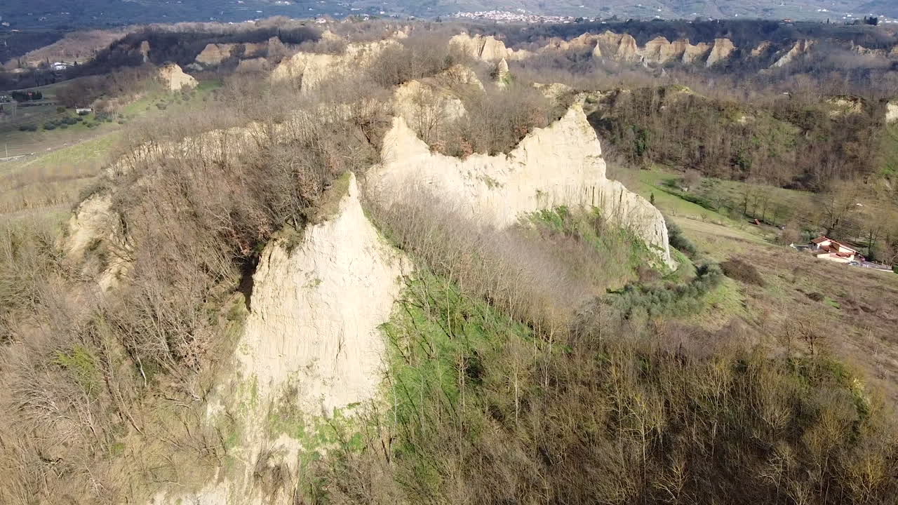 Orbiting Aerial flying drone shot over prehistoric age canyons Le Balze natural reserve near Reggello. Tuscany, Chianti area. Italy. Winter season, partially sunny sunset.