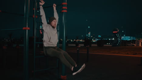 man doing hanging leg raises at a night street workout