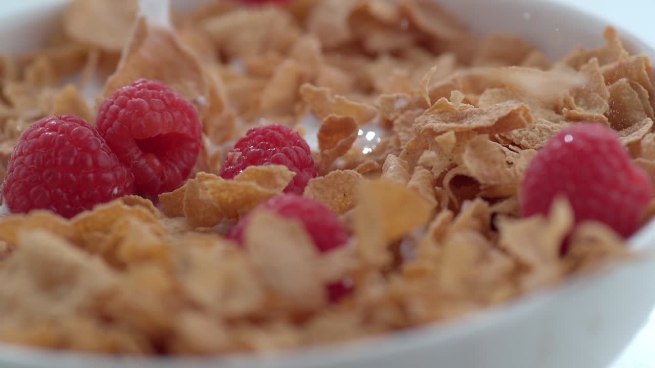 Lamponi che schizzano in una ciotola di cereali al rallentatore