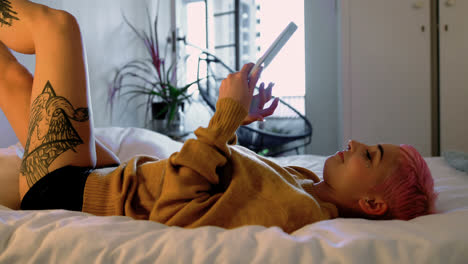 pink hair woman using digital tablet on bed in bedroom 4k