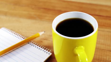 coffee mug, notepad and pencil on wooden plank