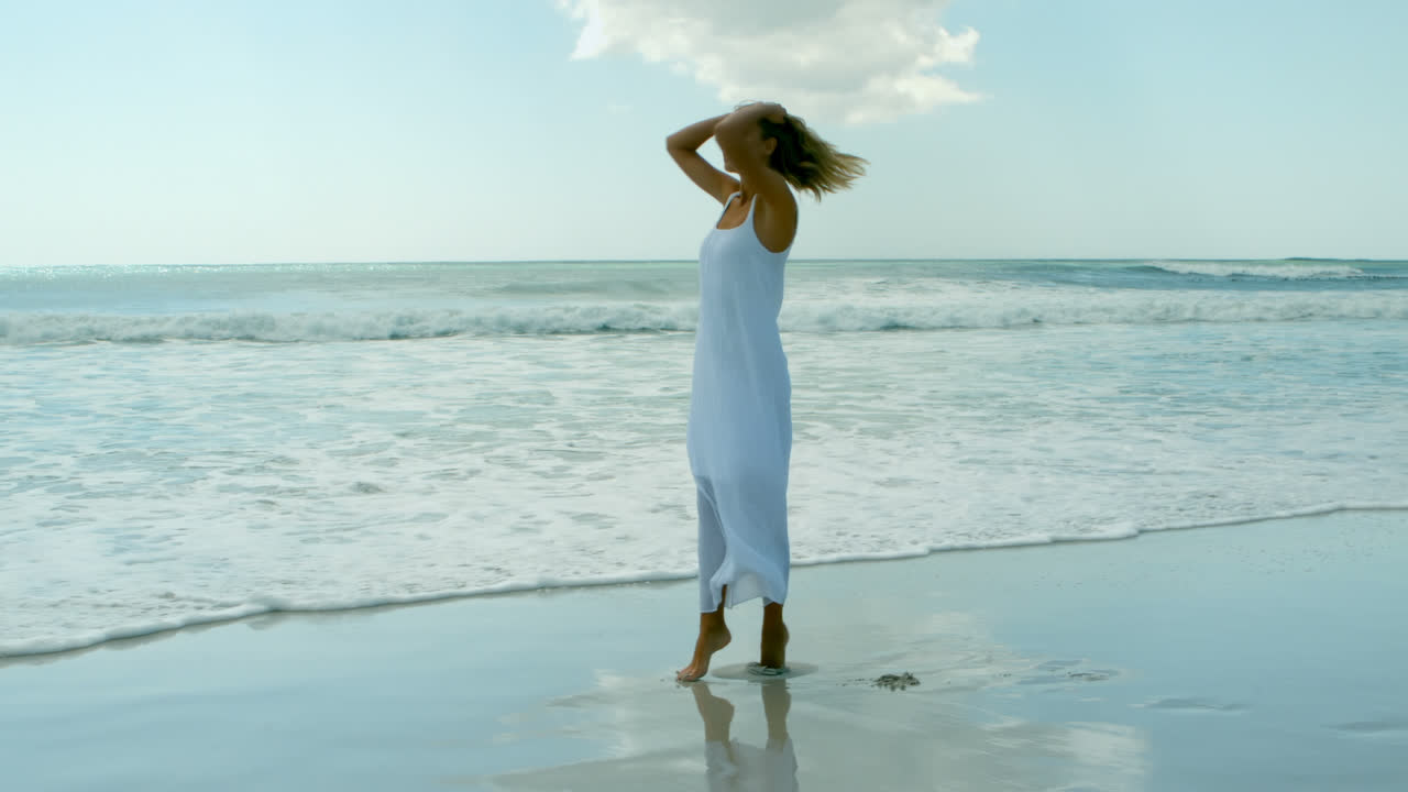 vista trasera de una joven mujer caucásica disfrutando de sus vacaciones en la playa 4k