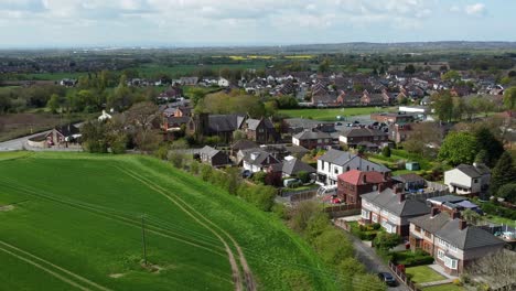 Aerial-view-rural-British-countryside-village-property-surrounded-by-farmland-fields,-Cheshire,-England