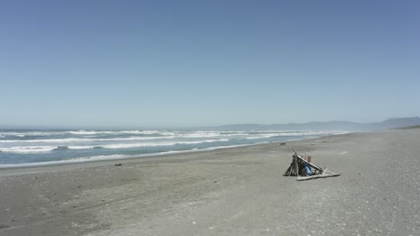 Person-sits-in-a-wooden-fort-on-the-beach