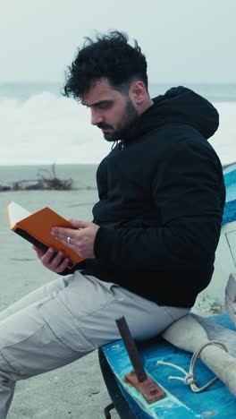 man on the beach in winter re reads his notes sitting on a boat