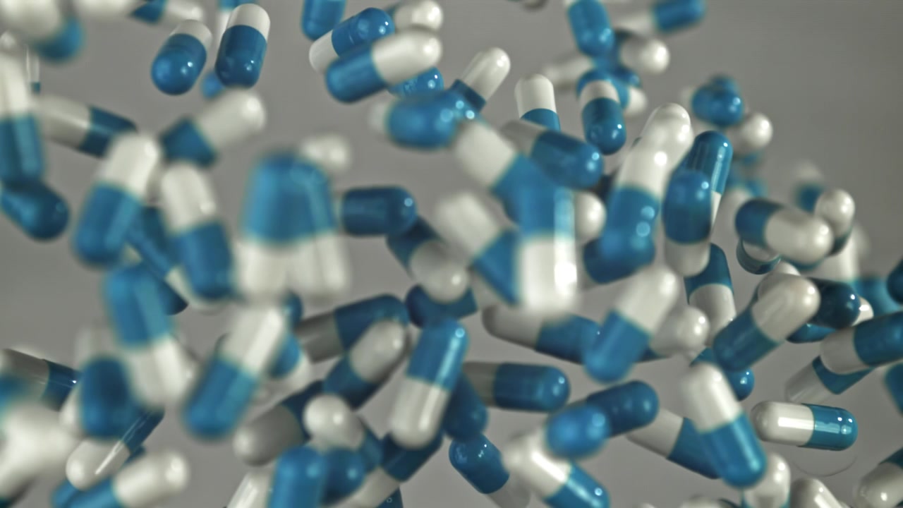Capsule farmaceutiche blu e bianche che cadono al rallentatore