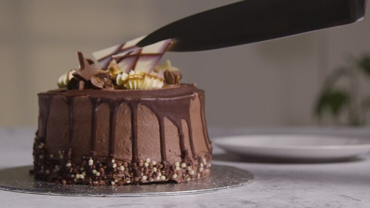Close Up Shot Of Person At Home Cutting Slice From Chocolate Celebration Cake On Table