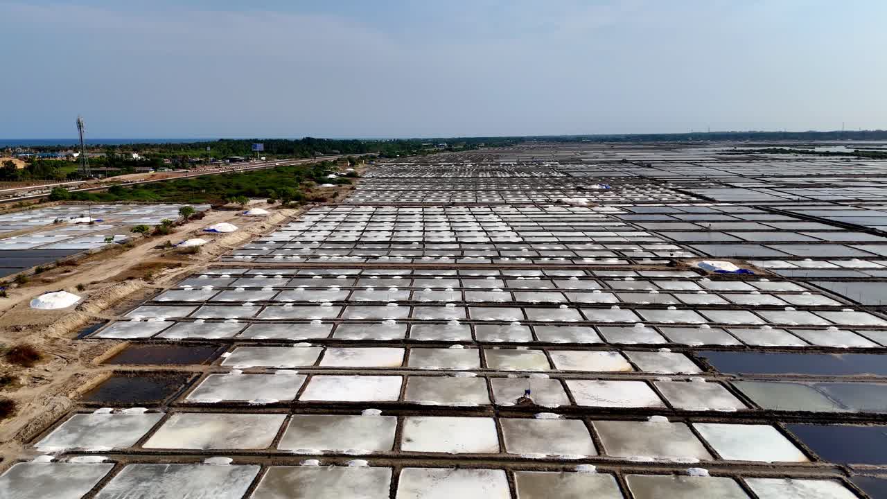 Aerial footage captures the contrast between geometric evaporation ponds and distant water and roads, highlighting the sun-drenched, industrial landscape and its connection to nature