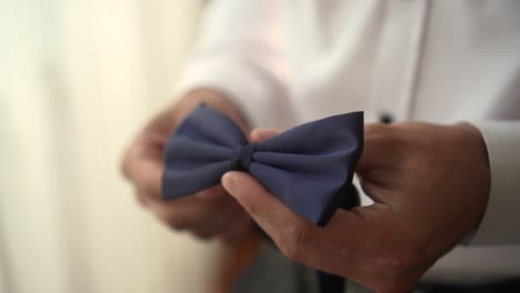 a man holds a bow tie in his hands