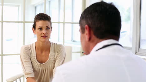 doctor speaking with his sick patient at desk