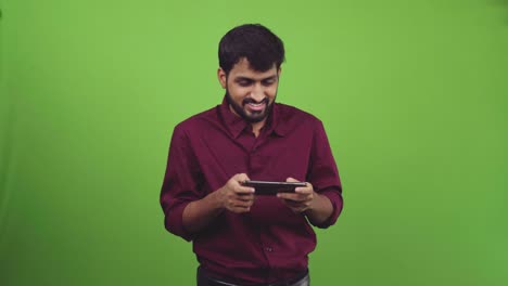 handsome man playing games on smartphone and wins, isolated on green screen