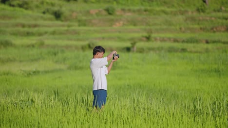 Indian photographer taking pictures in lush green paddy fields during monsoon, rural landscape photography scene, 4k video