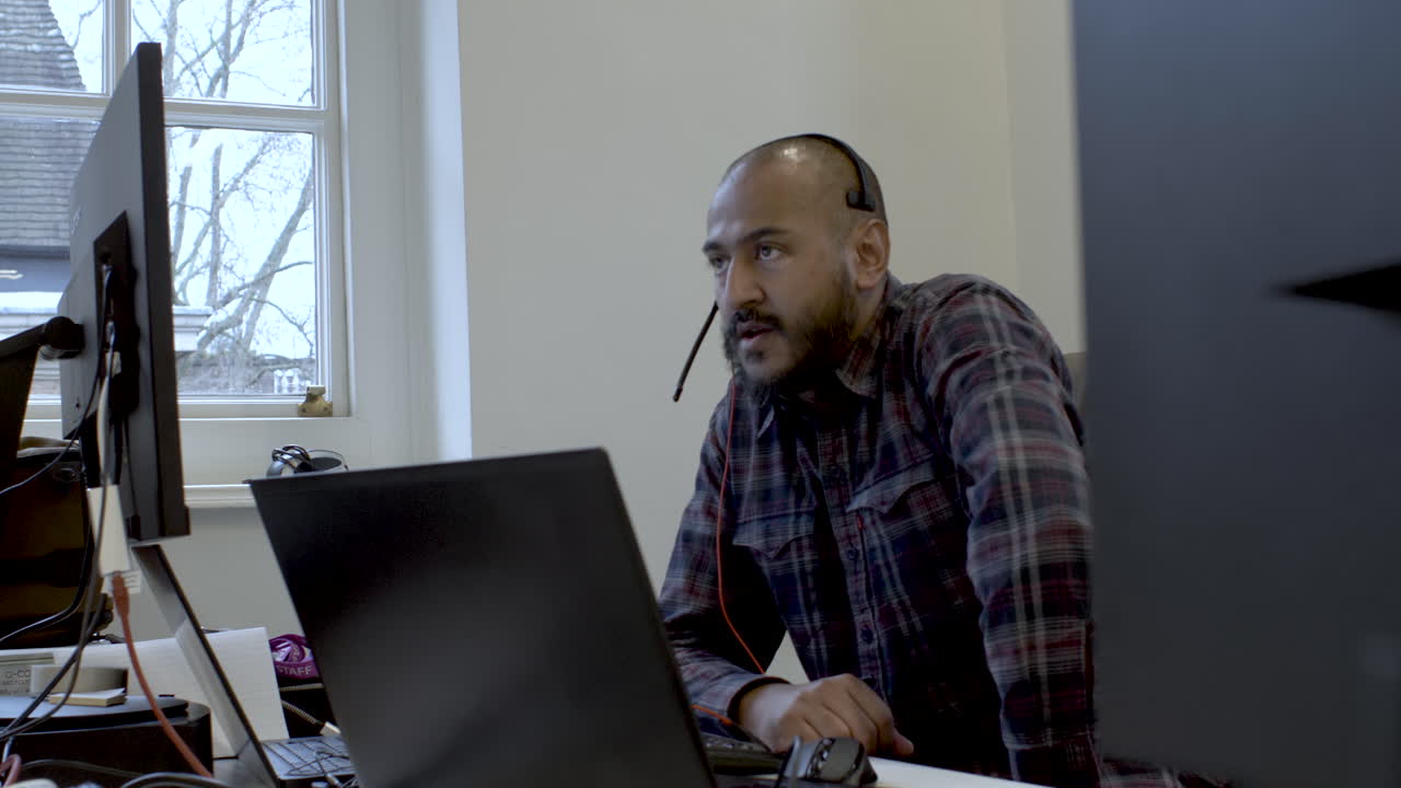 Male executive wears headset video calling on laptop