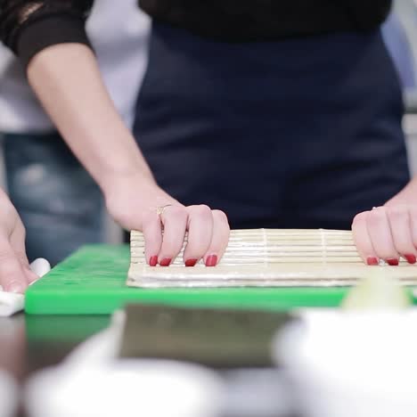 woman chef filling japanese sushi rolls