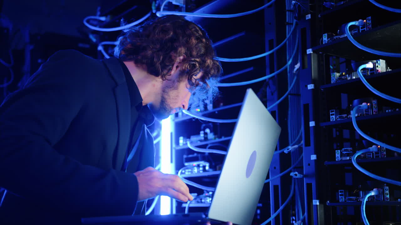 Man analysing servers and programming on a computer in a data center
