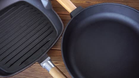 two new non-stick cast iron pans on a wooden background. grill pan with wooden handle, cooking accessories