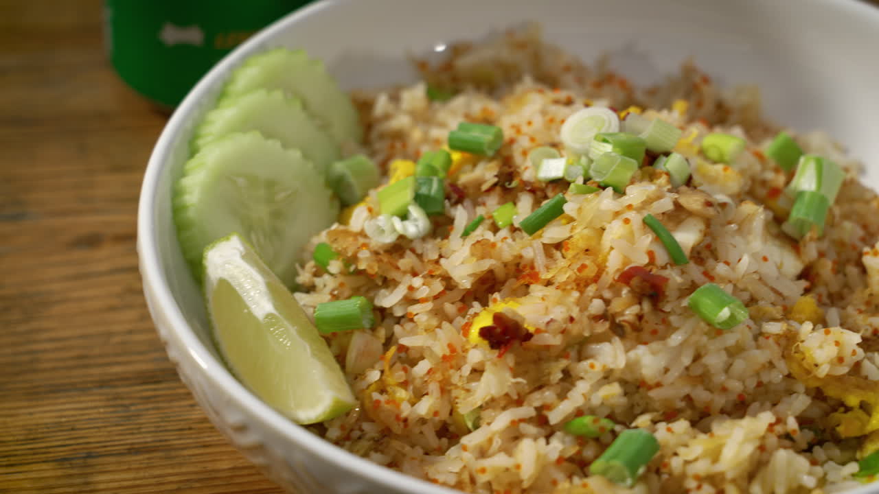 cuenco de tiro de mesa de arroz frito de cangrejo revestido con pepinos cortados y cebollas verdes, deslizador de cerca 4k