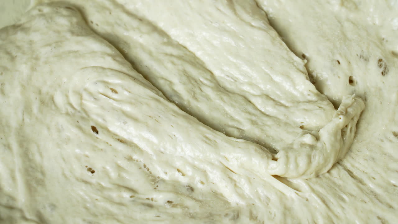 주방장이 실리콘 주걱으로 효모 반죽을 섞고 있습니다.