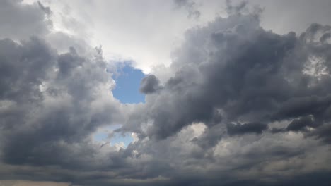 Blauer-Sommerhimmel-Mit-Dichten,-Dicken-Regenwolken,-Die-Sich-über-Den-Himmel-Bewegen