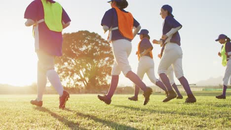 diverse group of female baseball players exercising on pitch, running and touching the ground