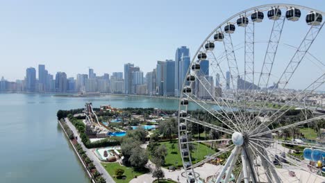 4k: aerial view of sharjah's khalid lake with city skyline and eye of emirates on a bright sunny day, united arab emirates