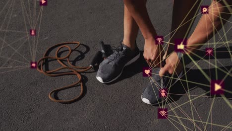 animation of media icons over african american man tying shoes