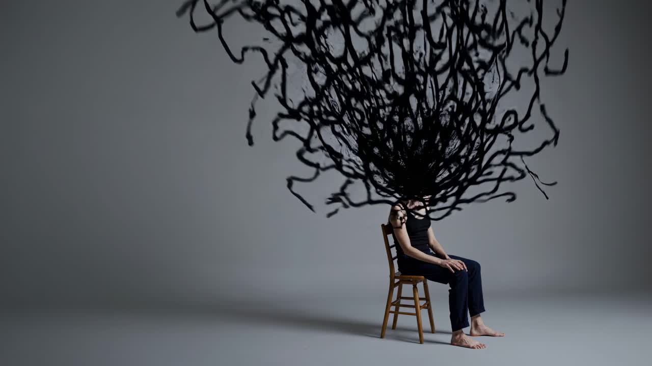Abstract black shape growing from woman's head as she sits calmly on chair against gray background, symbolizing complex thoughts, emotions, or mental state