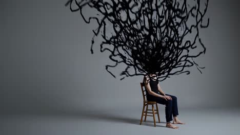 Abstract black shape growing from woman's head as she sits calmly on chair against gray background, symbolizing complex thoughts, emotions, or mental state