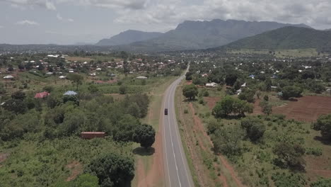 aerial tracks tour bus driving into picturesque plateau town in malawi