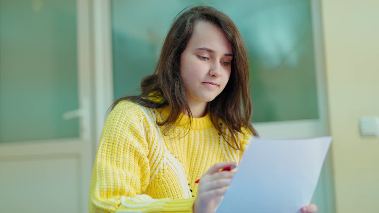 Girl student is reading. Portrait of female teenager sitting and checking her work in the classroom. Smart schoolgirl studying.