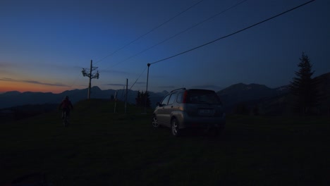 mountain biker closes car boot and rides away at dawn