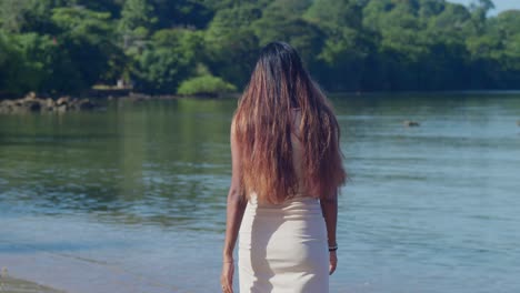 en un soleado día del caribe, una joven con un vestido de playa encuentra deleite caminando por la costa.