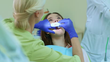 dentista con asistente preparando a la chica para el blanqueamiento de dientes. procedimiento de blanqueamiento
