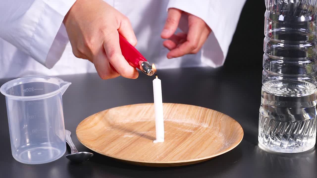 una persona con una bata de laboratorio enciende una vela en un plato, preparándose para un experimento de reacción química