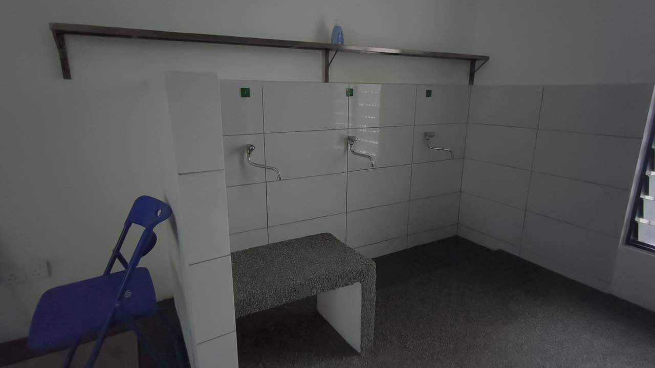 A close-up of a clean ablution area at a small Malaysian highway prayer room. Water flows for ritual washing as travelers prepare for prayer