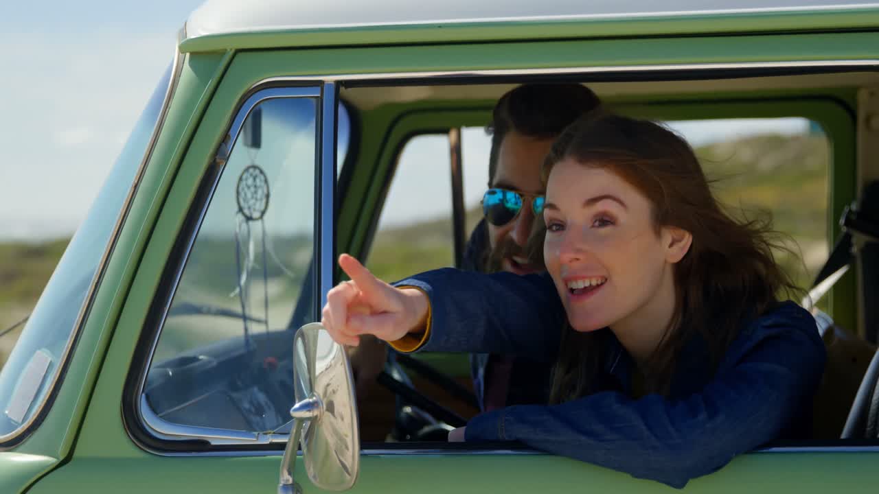 mujer hermosa sonriendo señalando con el dedo mostrando algo al hombre en el coche 4k