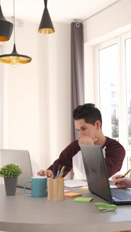 young man working from home on two laptops