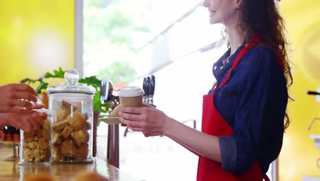 waitress serving coffee to male costumer at counter