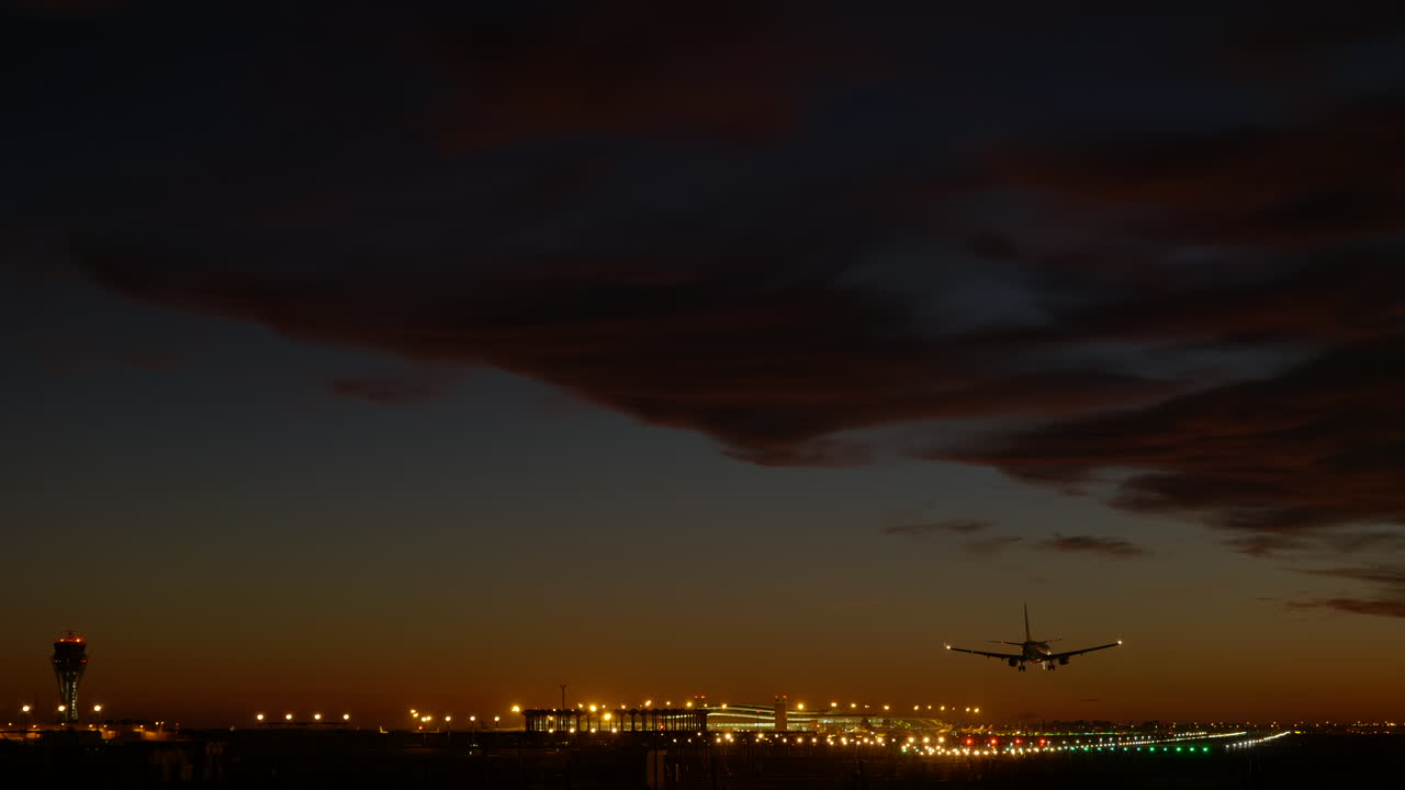 avión aterrizando al atardecer, aeropuerto de barcelona iluminado en segundo plano