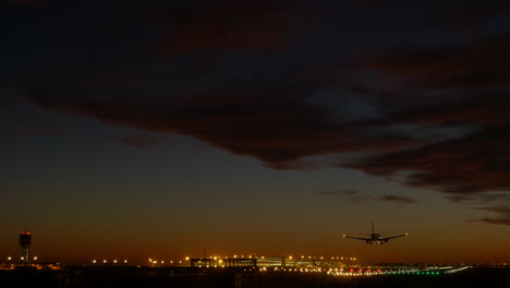 airplane landing at sunset, barcelona airport illuminated in background