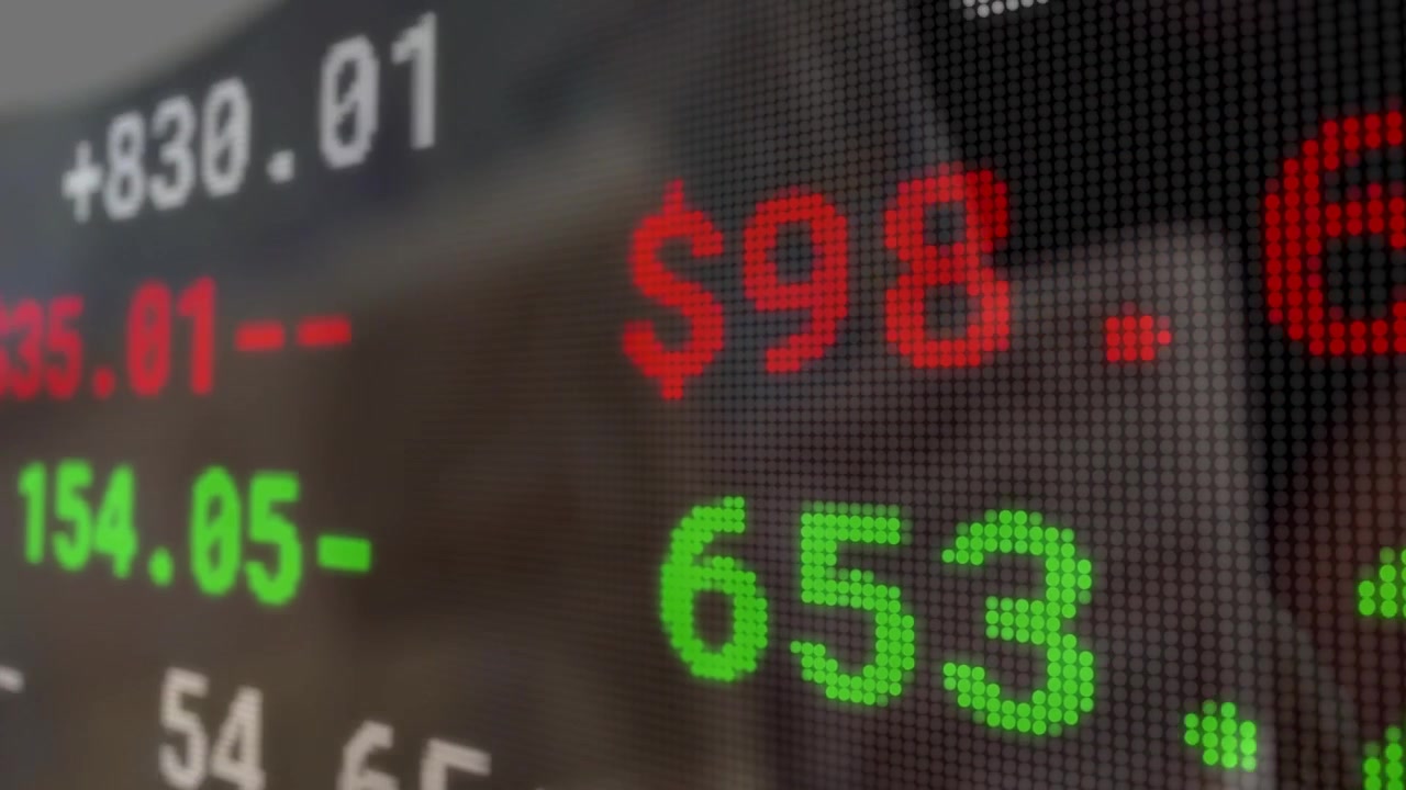 Overlay ticker di aggiornamento dati di mercato che si aggiorna e scorre, mentre una persona usa il tablet monitorando i dati.