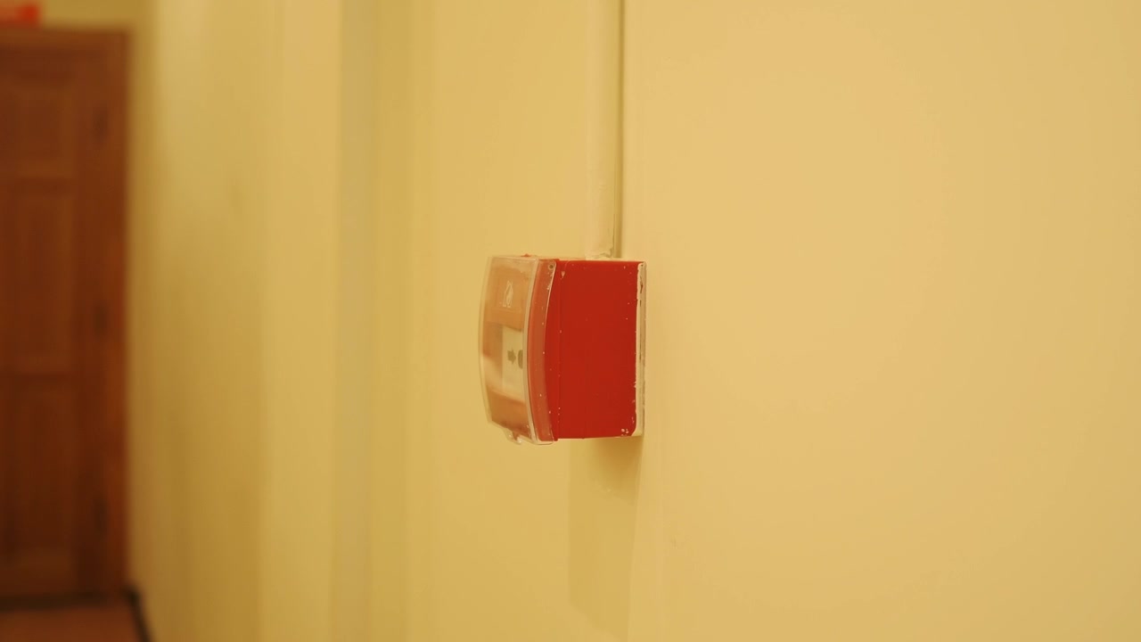 Red Fire Alarm Pull Station Mounted on a Beige Wall