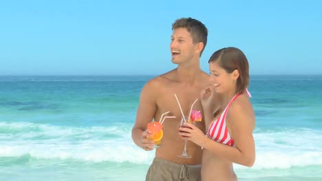 una hermosa pareja tomando bebidas en una playa.
