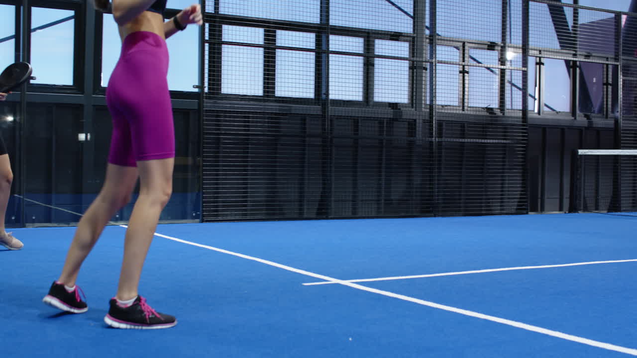 Playing padel tennis, two people enjoying match on blue indoor court on indoor court