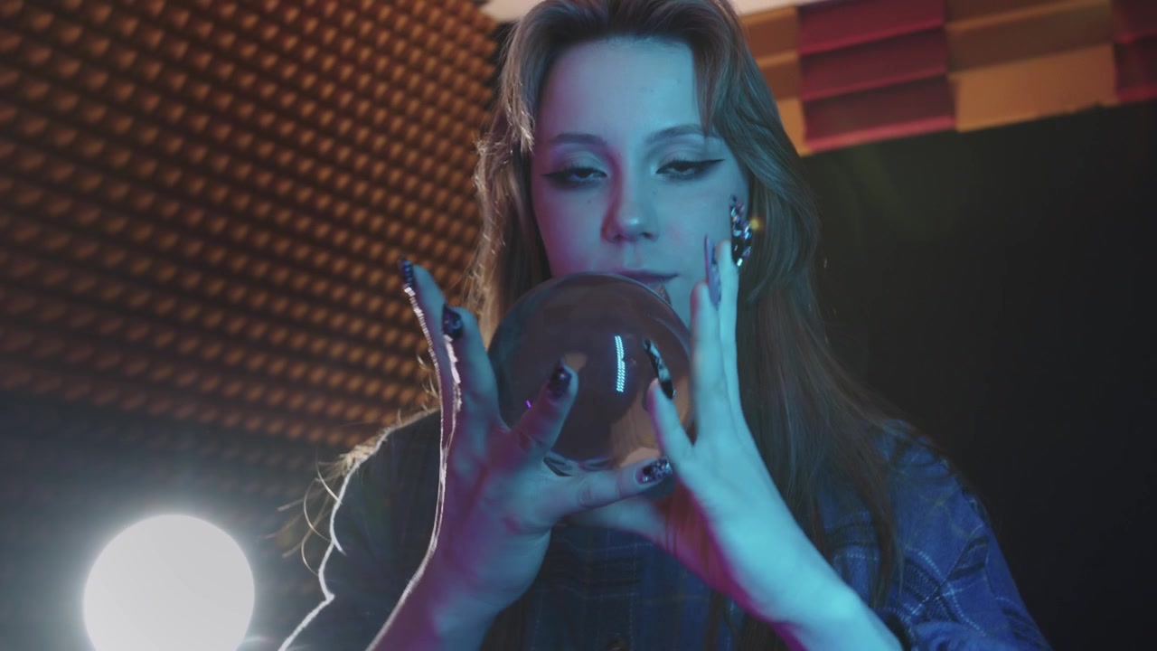 Una giovane donna che interpreta una strega mostra un trucco magico con una sfera di cristallo tramite contact juggling