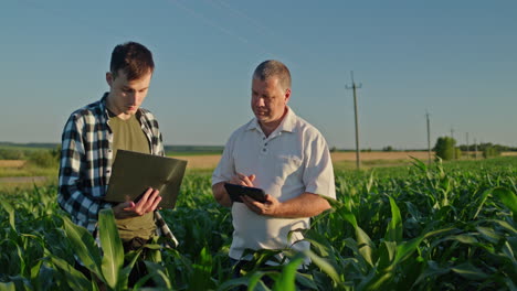 agricultor y consultor inspeccionando el campo de maíz con tecnología