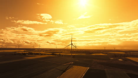 parallax drone shot of wind turbines in a wind farm at sunset with yellow sky, renewable energy