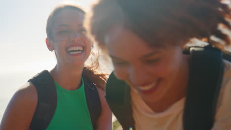 group of female friends with backpacks helping each other on hike in countryside on coastal path