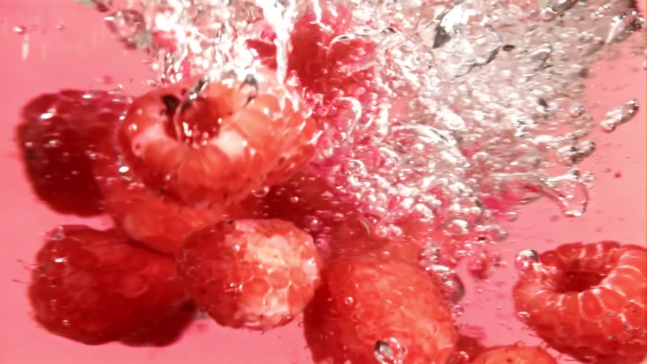 Fresh Red Raspberries Falling into Water with Bubbles